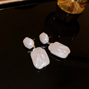 Macro shot of white baroque pearl star earrings on a sleek black reflective surface