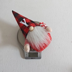 Vista di dettaglio che mostra il peso della bambola di gnomo di Natale in peluche a quadri.
