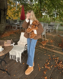 Detail van een bruin gewatteerd jack met vetersluiting, gedragen in een herfstachtige setting