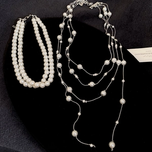 Detail view of multi-layer pearl fringe necklace with silver chains on black velvet