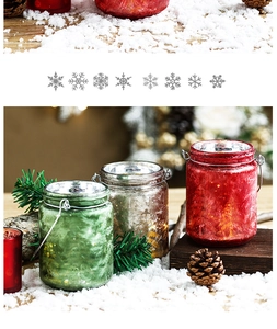 Close-up of festive Christmas crackle glass candle jars with metal handles in snow decor