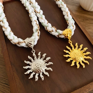 Detailed close-up of gold and silver sun pendants on woven bohemian cord necklaces