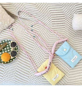 Close-up of minimalist nylon phone crossbody bags with pink straps and brand label details