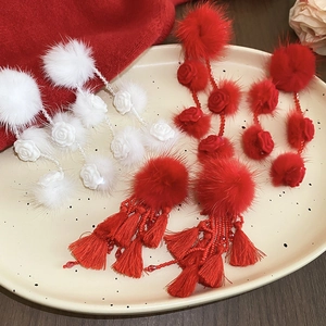 Detail of red and white plush pom-poms with tassel and rose floral earrings