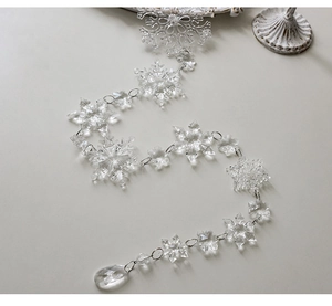 Macro detail of clear acrylic snowflake ornaments with faceted teardrop crystal pendants