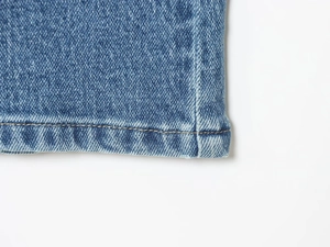 Detailed macro view of the double-stitched hem on these high-waist blue denim wide-leg pants