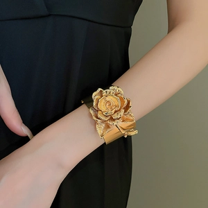 Macro detail of luxury wide gold open bangle featuring a 3D metallic rose flower design