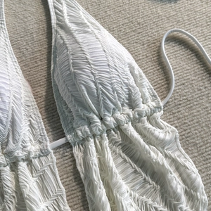 Detailaufnahme des weißen strukturierten Bikini-Oberteils mit gewelltem Faltenmuster