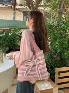 Detail of pink and white striped knit tote bag with large textured bow and thick strap