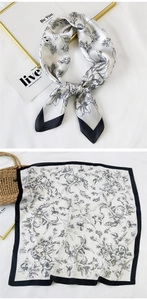 Detail of silk square scarf showing black floral print on white satin with tied styling