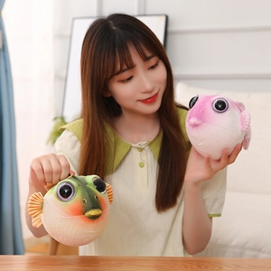 Détail de la peau de peluche poisson-globe douce en vert et rose avec de grands yeux