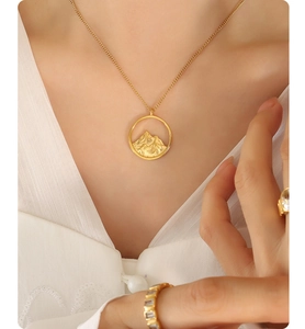 Detail of gold mountain landscape pendant necklace with elegant 3D texture on model