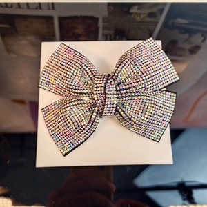 Detail shot of large crystal bow hair clip with iridescent rhinestones in a white box