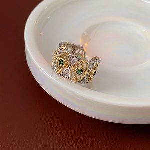 Dettaglio anello regolabile bicolore con pietre verdi e diamanti su piatto in ceramica