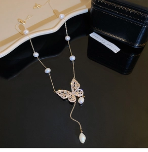 Detail of gold butterfly necklace featuring freshwater pearls and sparkling zircon fringe