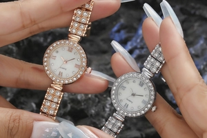 Detail of quartz watches with rhinestone crystals and Roman numerals on dark stone