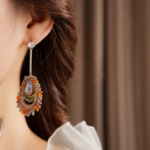 Macro detail of bohemian long drop earrings with iridescent gems and colorful beads