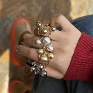 Anelli regolabili in oro e argento con sfere di metallo e perle sulla mano