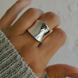 Close-up of polished silver wide band titanium steel ring on hand with knit sweater