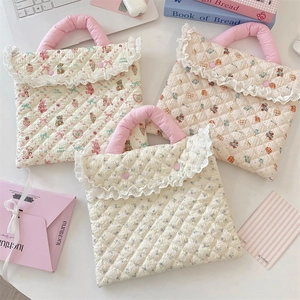 Detailed view of quilted cotton laptop sleeves with strawberry and floral lace patterns