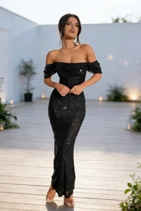 Détail d'une robe de soirée noire à paillettes, épaules dénudées et fente élégante