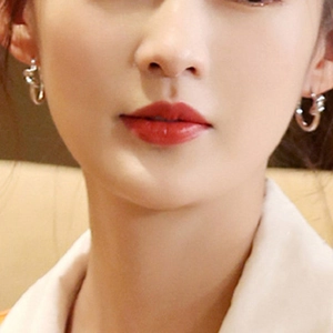 Minimalist silver knot hoop earrings in 316L stainless steel worn by a model