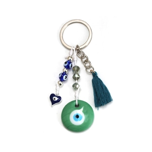 Detail of evil eye keychain with blue tassels and green bead charm on white background