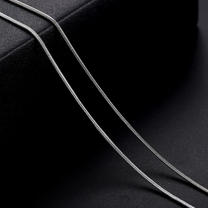 Close-up of two polished silver snake bone necklaces showing fine metal texture details