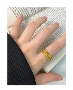 Macro detail of gold woven hollow lace ring on hand with vintage book background