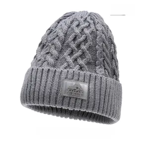 Dettaglio del cappello in maglia a trecce grigie con toppa logo montagna per calore invernale