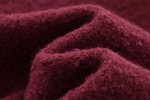 Gros plan sur un tissu bouclé rouge foncé texturé avec des fibres de laine douce