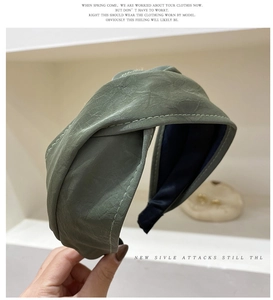Detail of dark green wide headband with pleated texture and stylish knotted design