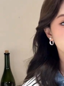 Close-up of elegant silver hoop earrings with white pearls worn by a model in a casual setting