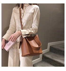 Detail of caramel brown leather bucket bag showing wide strap and smooth texture