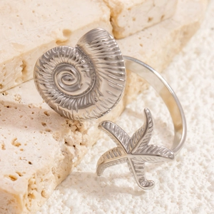 Detail of silver starfish and ammonite open ring on natural beach stone background