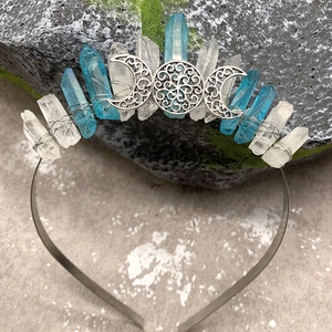 Close-up of triple moon crown featuring clear and blue raw crystals on mossy stone