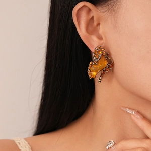 Close-up of vintage butterfly earrings with amber glass and diamonds on model