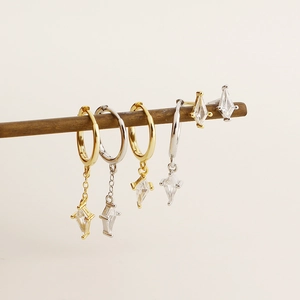 Détail de créoles en argent et or avec pendentifs en zircone rhombique sur support