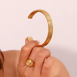 Close-up of three-layered gold-plated stainless steel cuff and spiral ring on model's hand