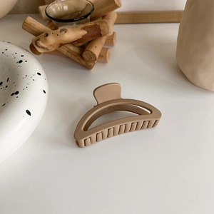 Close-up of matte apricot hair claw with hollow crescent design and durable spring