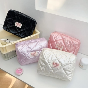Glossy puffer makeup bags in black, pink, purple, and white with quilted texture