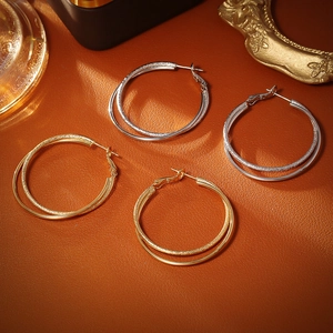 Chic double hoop earrings in gold and silver finish with textured details on leather