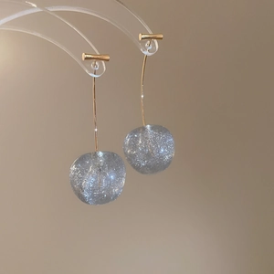 Détail de boucles d'oreilles pendantes cerise avec sphères en résine grise pailletée