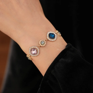 Macro shot of vintage gold bracelet featuring colorful gemstones and crystal diamond halo