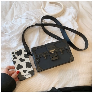 Close-up of vintage box crossbody bag with metal rivets and brand logo detail on lock