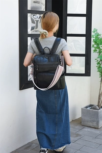 Detail view of black vintage backpack with decorative geometric pattern strap on model
