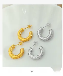 Details von gold- und silbernen C-Ohrringen mit Steppmuster auf einer Schale
