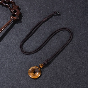 Macro shot of tiger eye stone donut pendant with adjustable brown braided cord