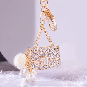 Elegant gold metal handbag keychain with white rhinestones and pearl charms