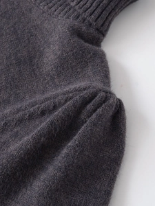 Detailed macro view of dark grey knit fabric featuring pleated shoulder and ribbed edge finish